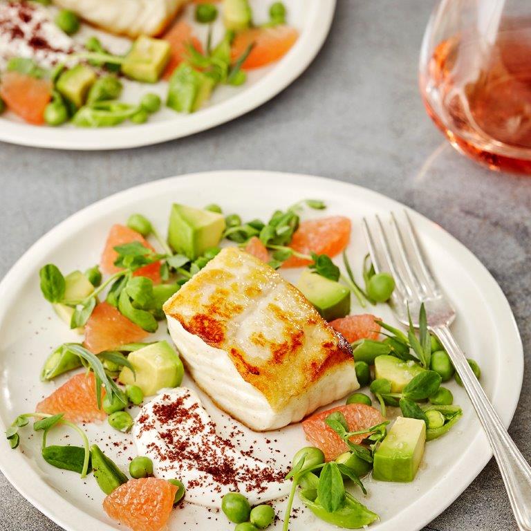 A plated dish of Halibut, peas, avocado and Grapefruit.